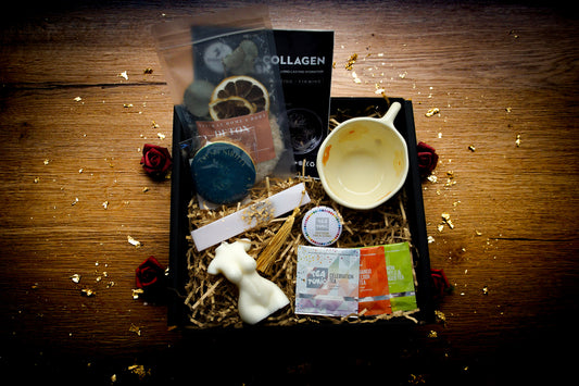 Small Pleasures self-care gift box featuring a wrapped mystery book, ivory Venus torso candle, bookmark and floral ceramic teacup